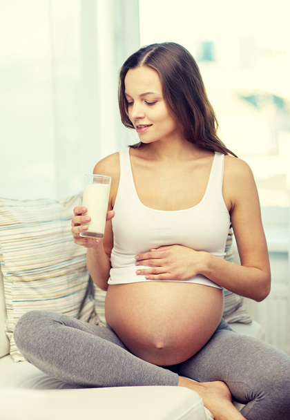 happy pregnant woman drinking milk at home - Foto, afbeelding