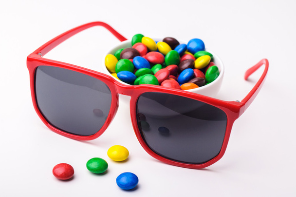 rode zonnebril en kleurrijke snoepjes - Foto, afbeelding