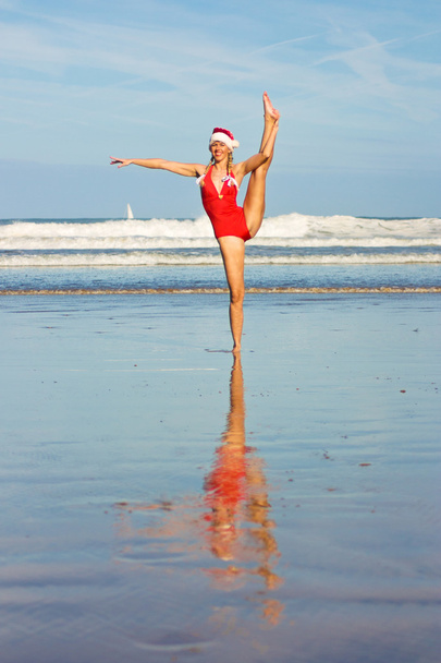 Mujer en sombrero de Navidad haciendo de pie splits
 - Foto, Imagen