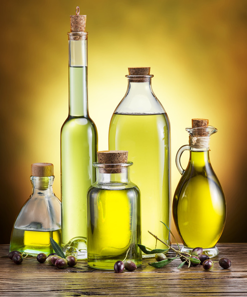 Glass bottles of olive oil and few berries on the wooden table. - Photo, Image