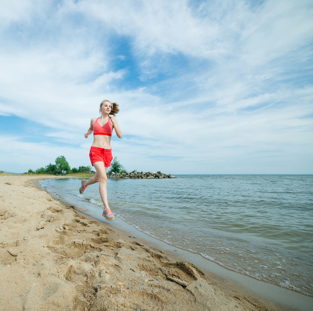 Νεαρή κοπέλα που τρέχει στην παραλία άμμου ηλιόλουστο καλοκαίρι. Προπόνηση. Σπρώχνω - Φωτογραφία, εικόνα