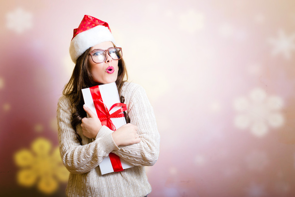 Pretty girl in Santa hat surprised holding giftbox with snowflakes - Zdjęcie, obraz