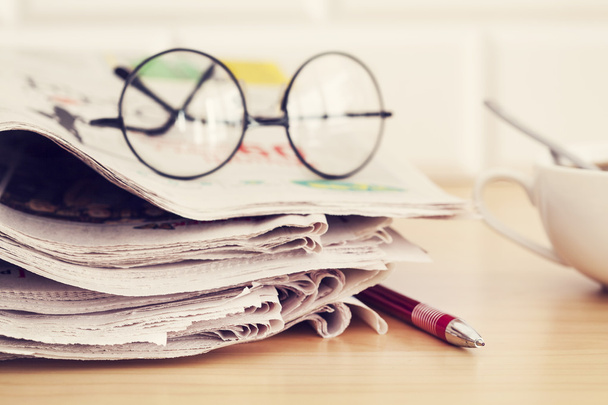 Stack of newspapers, eyeglasses on table - Foto, afbeelding