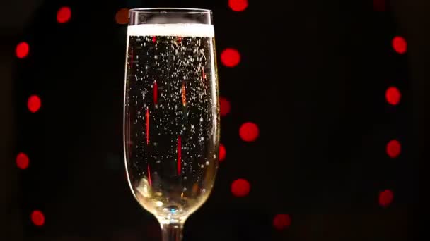 Bir bardak şampanya tatil ışıklar arka planı içinde baloncuklar - Video, Çekim