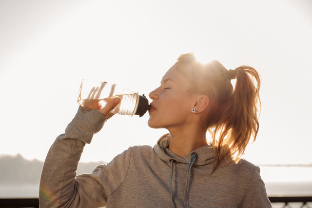 Jovem mulher bebendo água após o ciclismo
 - Foto, Imagem