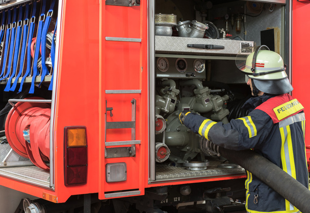Feuerwehrmann bringt Feuerwehrschlauch zum Einsatzfahrzeug. - Foto, Bild