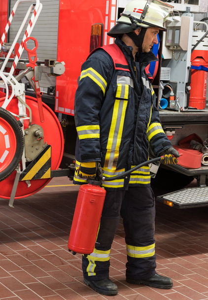 Brandweerman in actie en gebruikt een brand-extinguishe - Foto, afbeelding