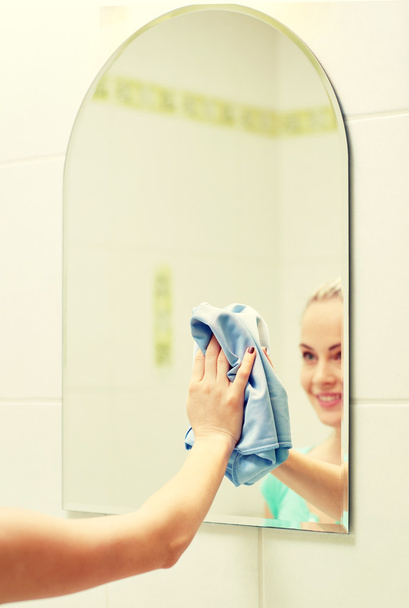 close up of happy woman cleaning mirror with rag - 写真・画像