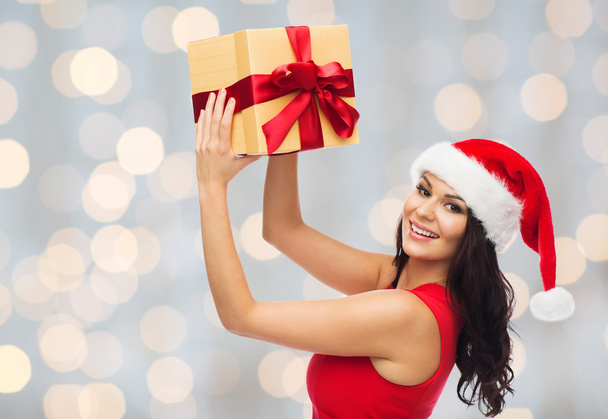 beautiful woman in santa hat with gift over lights - Photo, image