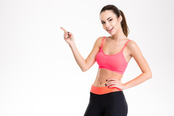 Cheerful attractive young fitness woman pointing away - Valokuva, kuva