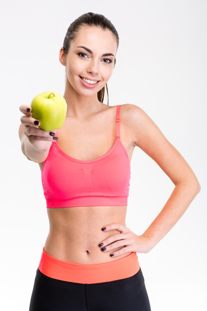 Pretty positive young sportswoman giving an apple - Foto, imagen