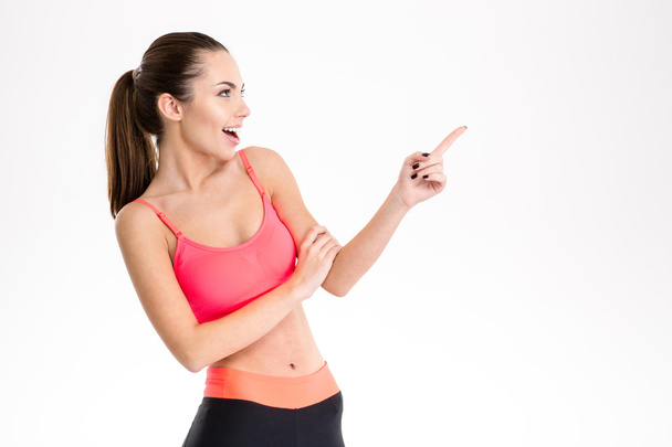 Excited content pretty fitness girl in sportwear pointing away  - Photo, image