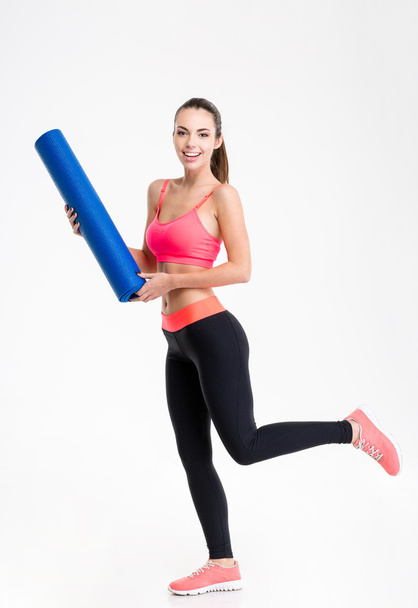 Pretty positive fitness woman running on training with  yoga mat - Foto, imagen