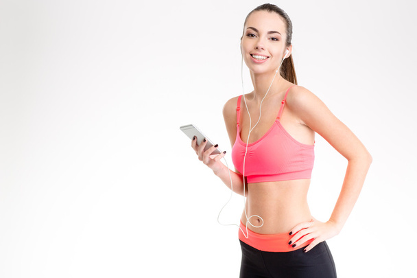 Fitness girl listening to music from cell phone using earphones  - Zdjęcie, obraz