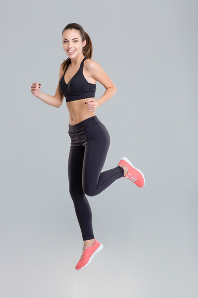 Cheerful active young sportswoman in fitness wear running  - 写真・画像