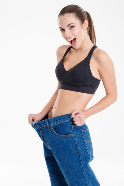 Amazed happy fitness woman became skinny and wearing old jeans  - Фото, зображення