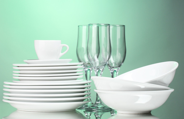 Clean plates, cup and glasses on green background - Zdjęcie, obraz