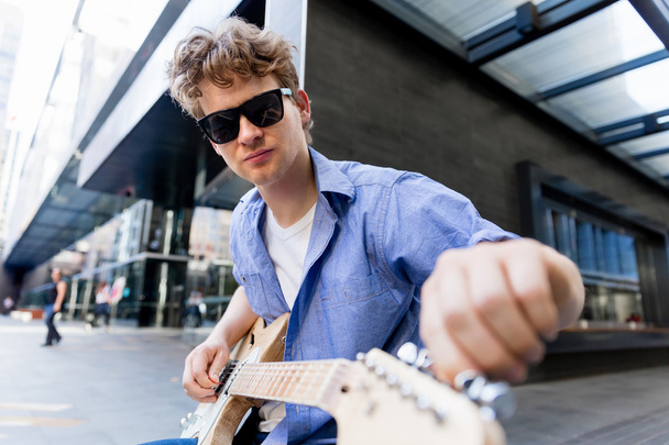 Молодой музыкант с гитарой в городе
 - Фото, изображение