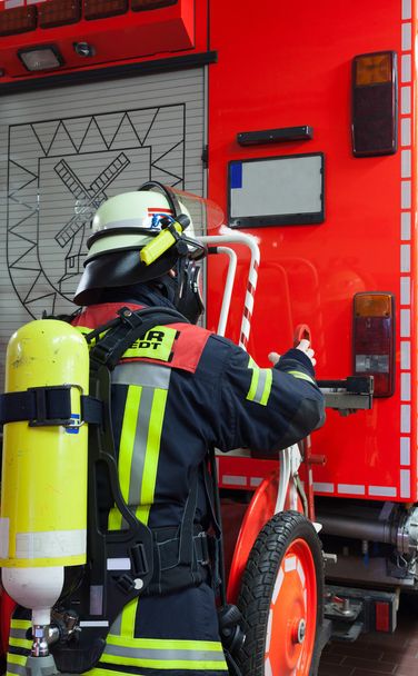 酸素ボンベや消防車のマスクとアクションの消防士 - 写真・画像