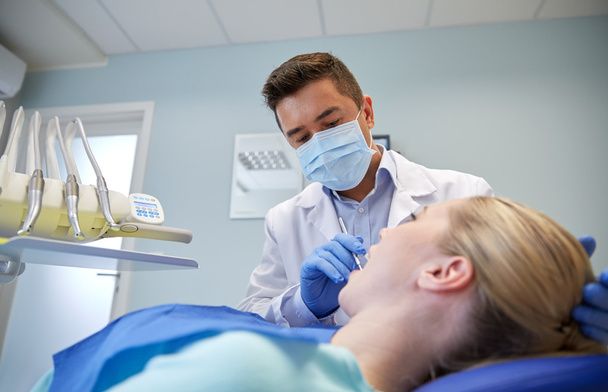 male dentist in mask checking female patient teeth - Valokuva, kuva