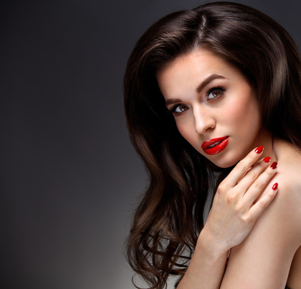 Beauty Model Woman with Long Brown Wavy Hair. Healthy Hair and Beautiful Professional Makeup. Red Lips and Smoky Eyes Make up. Gorgeous Glamour Lady Portrait. Haircare, Skincare concept - Фото, изображение