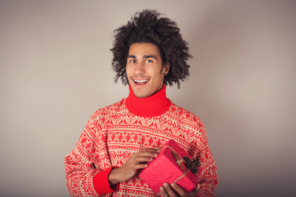 Portrait of young man with afro holding a Christmas gift - Photo, Image
