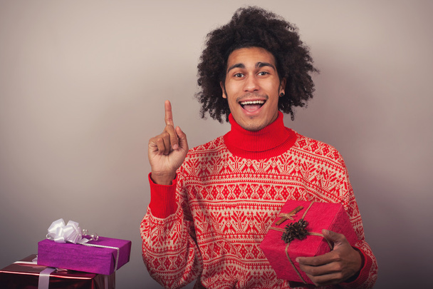 Portret młodzieńca z afro trzyma prezent na Boże Narodzenie - Zdjęcie, obraz