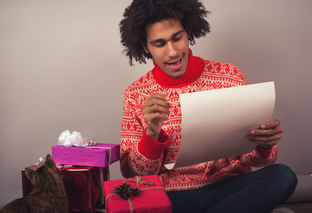 Portrait de jeune homme avec afro préparant une lettre de Noël ou une liste de souhaits
 - Photo, image