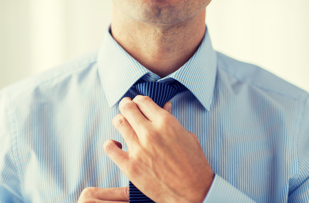 close up of man in shirt adjusting tie on neck - Фото, зображення