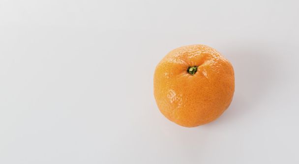 One tangerine on a white table - Φωτογραφία, εικόνα
