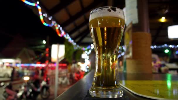 Glas schäumendes frisch gezapftes Bier auf der Theke in der Nachtstraße - Filmmaterial, Video