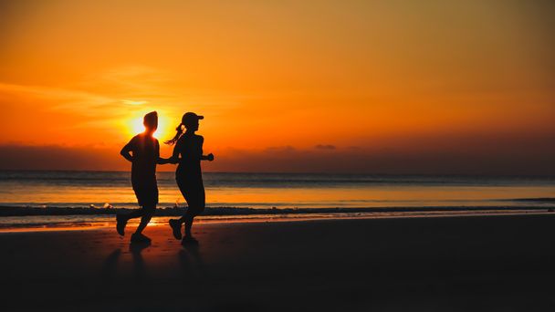 Jeune couple : homme et femme courent ensemble sur un coucher de soleil sur le lac de cacao
 - Photo, image