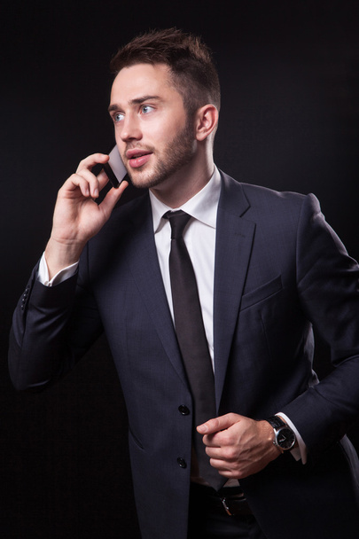 stylish, trendy businessman in a business suit on a black backgr - Foto, afbeelding