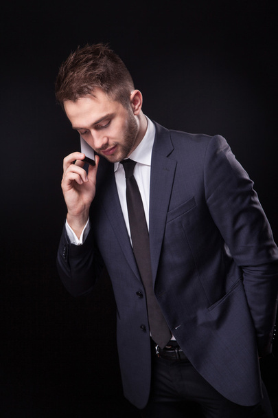 stylish, trendy businessman in a business suit on a black backgr - Foto, Bild