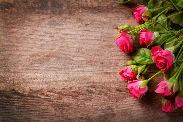 Beautiful bouquet of pink little roses on wooden background, copy space - Fotó, kép