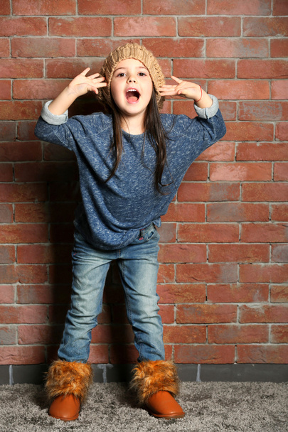 Portrait of little fashion kid girl on bricks wall background - Foto, imagen