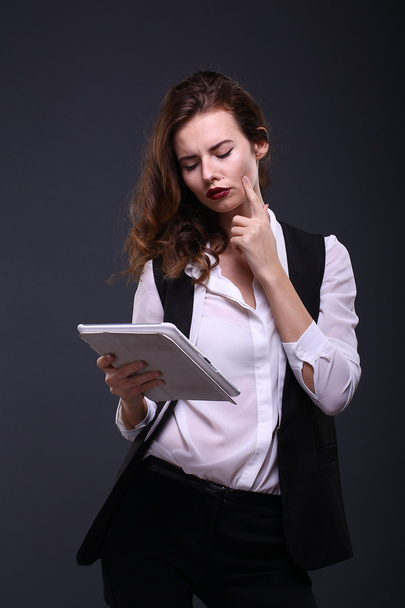 Portrait of a beautiful woman with white tablet on dark background. Studio shot. - Φωτογραφία, εικόνα