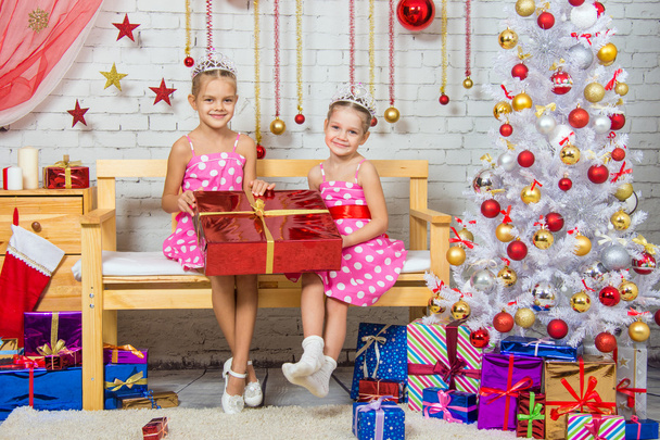 glückliches Mädchen, das ein tolles Geschenk machte, sitzend auf einer Bank in einem weihnachtlichen Rahmen - Foto, Bild