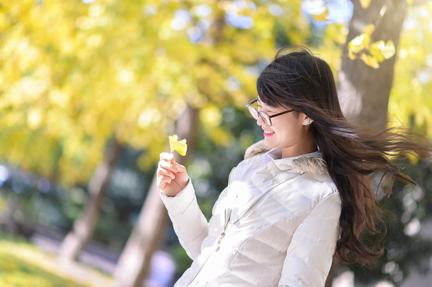Pretty Chinese girl dresses down coat in the sunshine day - Photo, Image