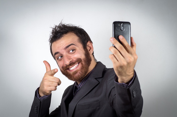 Забавный бизнесмен использует свой смартфон, чтобы сделать селфи
 - Фото, изображение