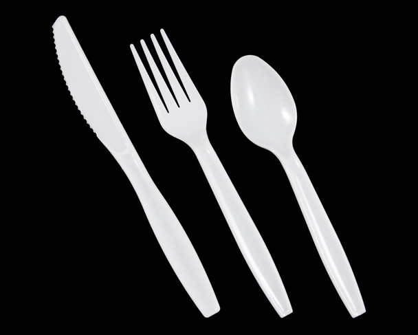 Cuchillo plástico blanco, tenedor y cuchara sobre fondo negro
.  - Foto, Imagen