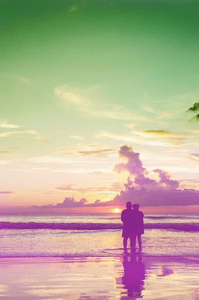 Εραστές χαλαρώστε στην παραλία στο χρώμα του ηλιοβασιλέματος - Φωτογραφία, εικόνα