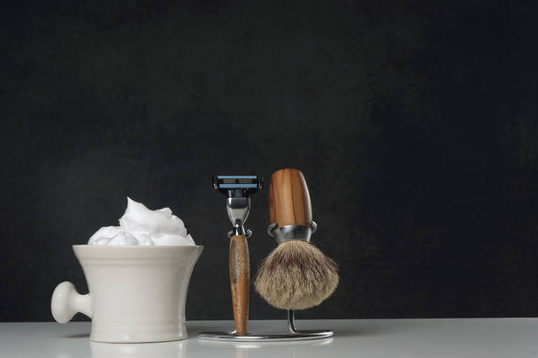 Equipo de afeitado vintage sobre mesa blanca y fondo oscuro
 - Foto, imagen