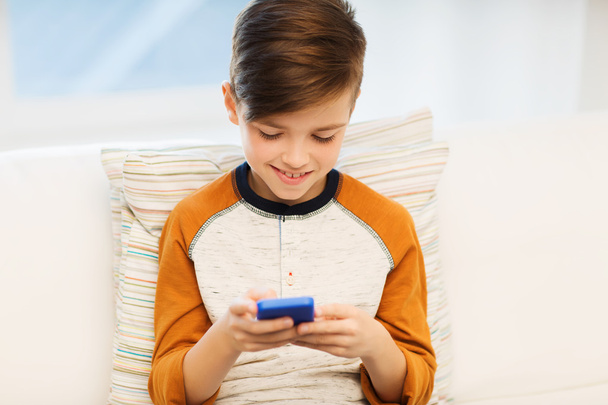 boy with smartphone texting or playing at home - Фото, изображение