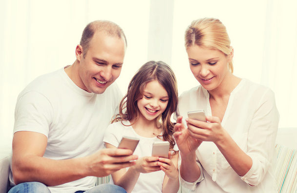 parents and little girl with smartphones at home - 写真・画像