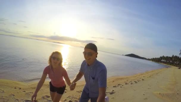Styl życia szczęśliwy para działa na piaszczystej plaży o zachodzie słońca - Materiał filmowy, wideo