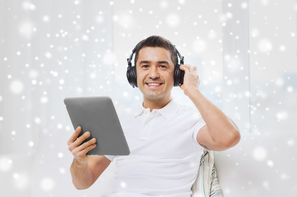 smiling man with tablet pc and headphones at home - Foto, afbeelding