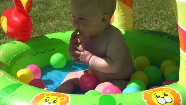 petite fille bébé joue dans la piscine gonflable à l'eau avec une petite boule. 4K
 - Séquence, vidéo