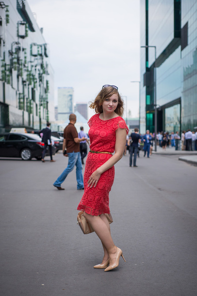 The girl in the dress of coral is among the skyscrapers of the business center - Fotografie, Obrázek