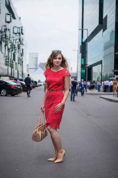 The girl in the dress of coral is among the skyscrapers of the business center - Fotografie, Obrázek